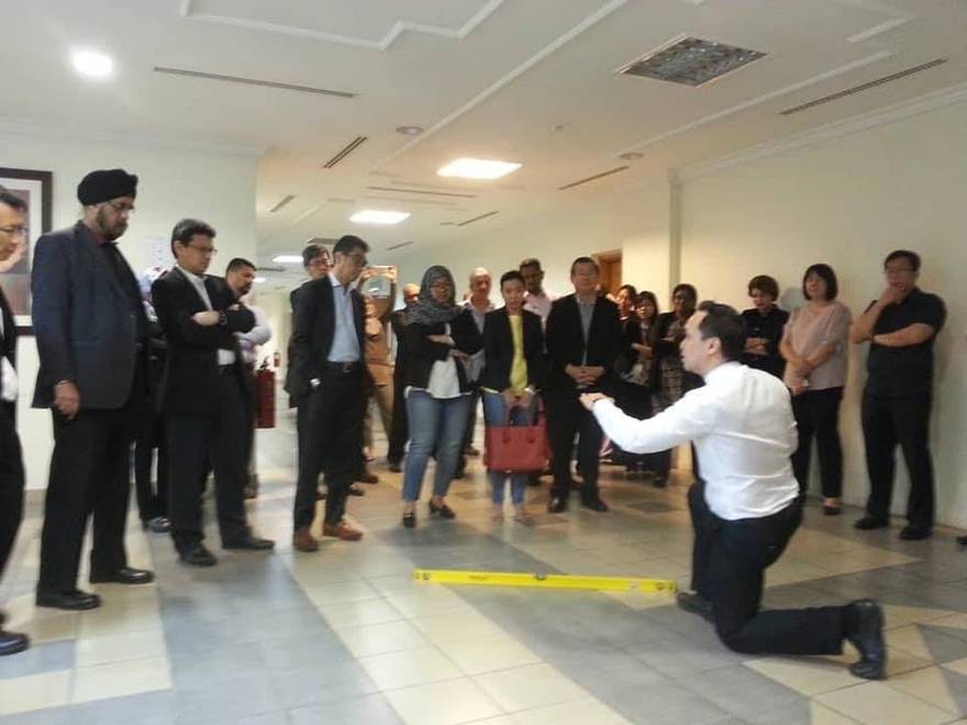 Sr Joshua Kang demonstrating floor level defect checks with a spirit level to homebuyers and industry professionals